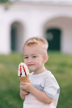 Portrait of a little boy. A baby eats a delicious ice cream cone. Happy child. Summer day