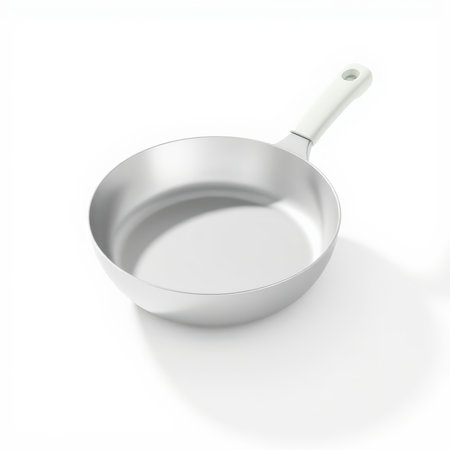 A clean, shiny silver frying pan with a light beige handle is presented at an angle on a crisp white background, casting a soft shadow.の素材