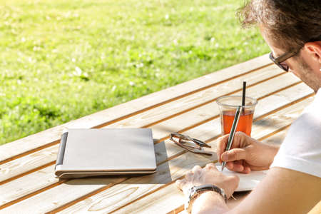 The young man writes in his notebook