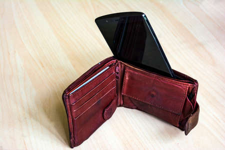 Paying with smartphone - mobile payment concept, cell inside instead of banknotes. Selective focus.