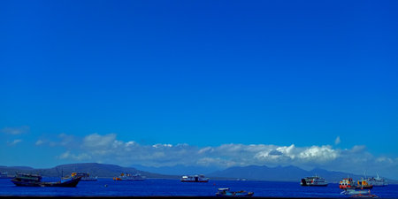 stunning ocean view with a vibrant blue sky, showcasing ships and distant mountains, perfect for...