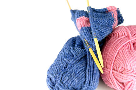 Knitting. Two balls two needles with a cloth on a white background