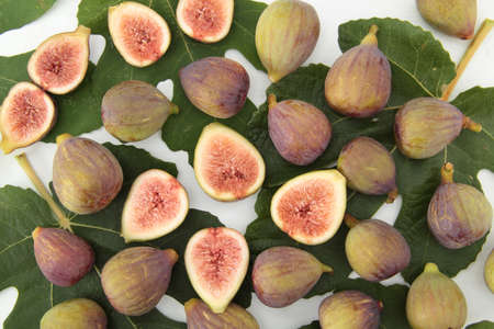 Fresh figs in composition with leaves on white table