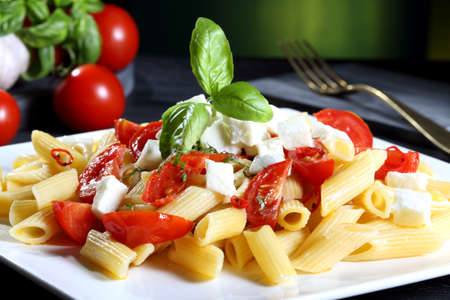 italian macaroni pasta with tomato and mozzarella green backgroundの写真素材