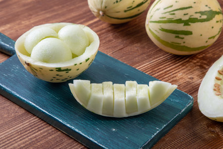 Melon on a blue cutting board. Green melon on a wooden table.