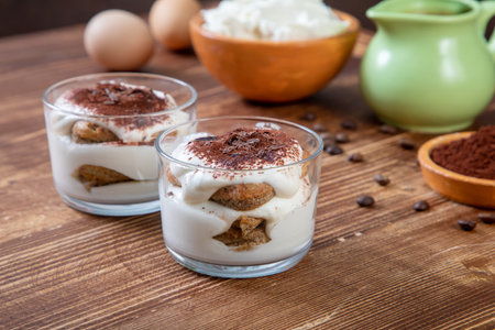Classic tiramisu dessert in a glass and ingredients on wooden backgroundの写真素材