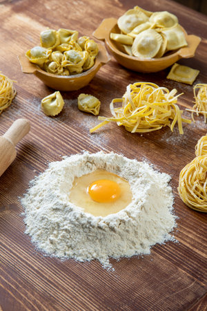 Homemade raw pasta with flour and egg on wooden table closeupの写真素材