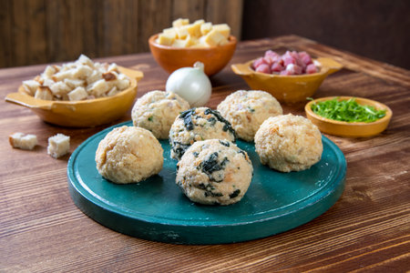 Meatballs with spinach and cheese on a blue plate on a wooden backgroundの写真素材