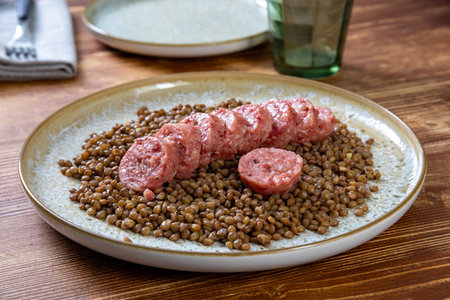 Lentils with sausages on a plate on a wooden tableの写真素材