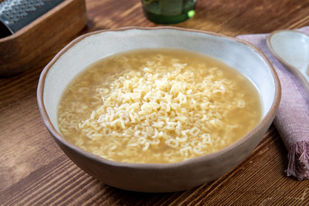 Rice soup with pasta in a bowl on a wooden table.の写真素材