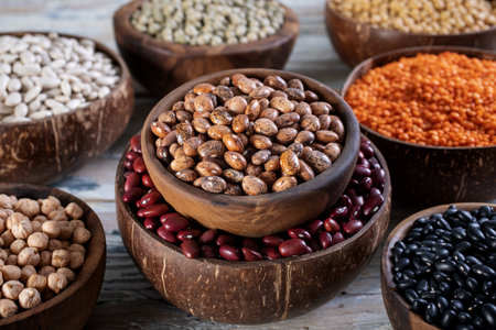 Assortment of different legumes in bowls on wooden background, close upの写真素材