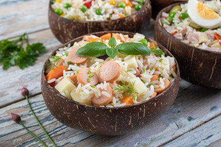 Rice salad with sausages in coconut shell on wooden backgroundの写真素材