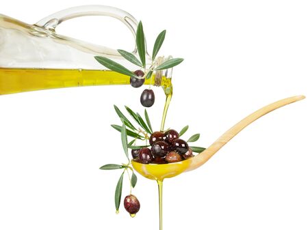olive oil flows from a bottle in a wooden spoon with branches of an olive tree. Isolated over white background. の写真素材