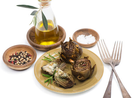 A plate with cooked artichokes,  served with olive oil,  pepper and salt  isolated on white background.の写真素材