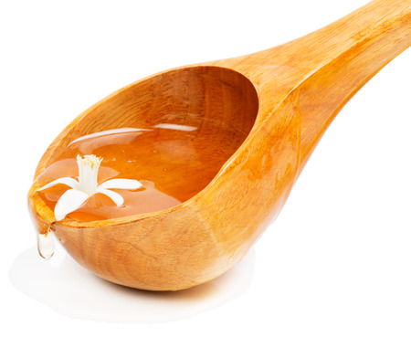 honey dripping from a wooden  ladle and flower of an orange tree, isolated on white background の写真素材