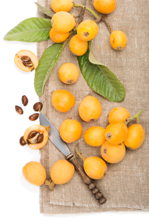 loquats with leaves on a  linen napkin on a white backgroundの写真素材