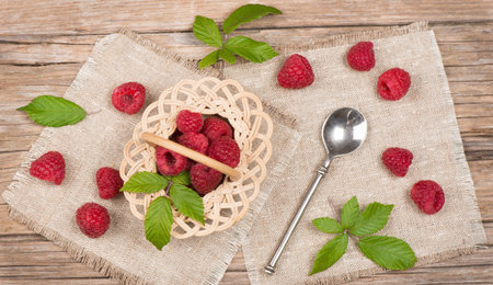 View from above of wicker basket with raspberries on wooden tableの写真素材