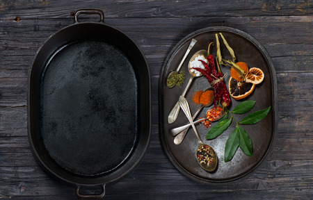 set of spices and opened empty cast iron saucepan from the top on awooden table