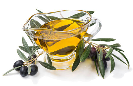 Sprigs of olive tree with black fruits and olive oil  in a glass dish isolated on whiteの写真素材