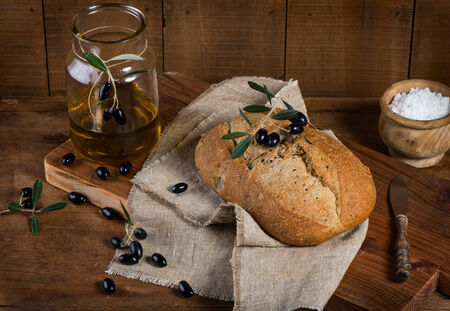 Olive bread, black olives and olive oil on a rustic wooden background