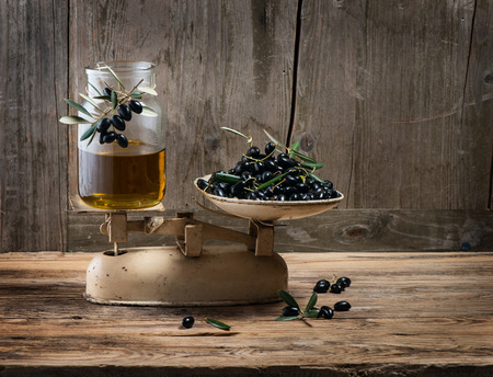 Weighing fresh olives and olive oil on vintage scales, with space for text on a wooden old backgroundの写真素材