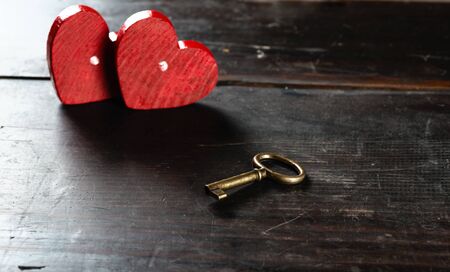 Key and two hearts on old wooden table, selective focus on the keyの写真素材