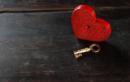 vintage key and red heart on a old dark wooden backgroundの写真素材