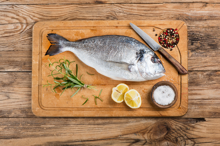 Top view of fresh dorado fish with spices on wooden cutting board.の写真素材