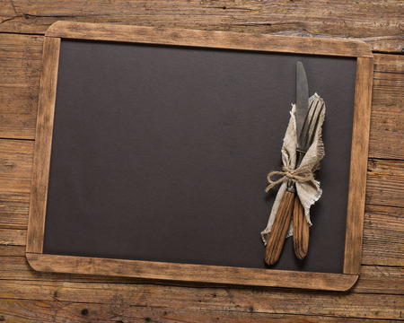 Top view of vintage fork and spoon tied with string on linen napkinon a blackboard on a old wooden table with copy space.の写真素材