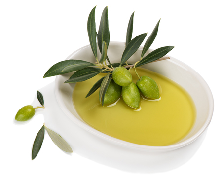 Twig with green olives in a white ceramic bowl with olive oil isolated on a white backgroundの写真素材