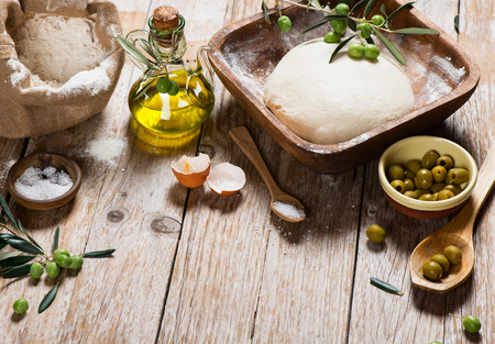 Preparations for baking of bread with olives on a rustic wooden background with copy space.の写真素材