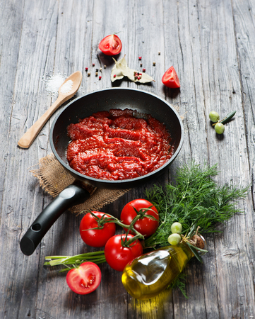Freshly cooked homemade tomato sauce on a rustic wooden background.の写真素材
