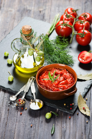 Fresh organic tomato sauce, spices, fresh tomatoes and olive oil on a black slate board on a rustic wooden table.の写真素材