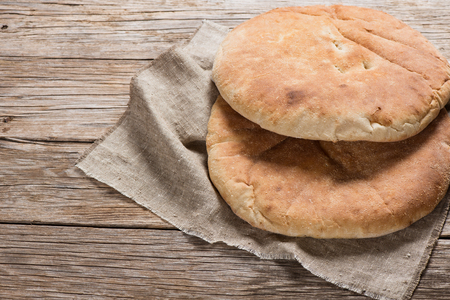Two pita bread on a linen napkin on a rustic  wooden background.の写真素材