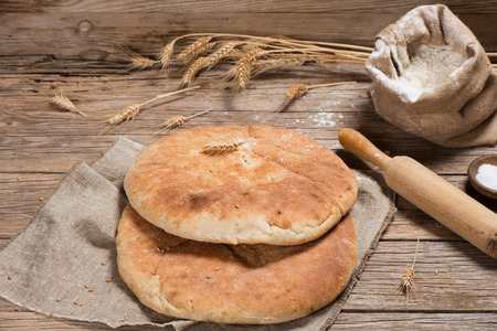 Freshly baked pita bread and ingredients on a rustic wooden background.の写真素材