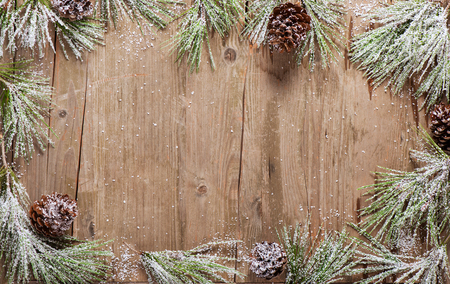 Christmas frame made from branches and cones of pine covered with snow on a wooden boards with copy space. Christmas background.の写真素材