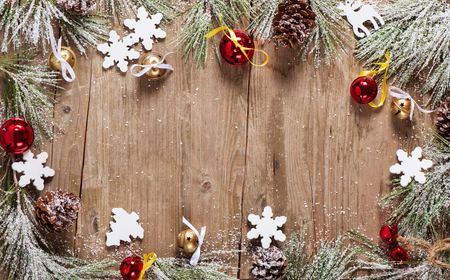 Christmas wooden background with snow, pine, cones and jingle bells.の写真素材