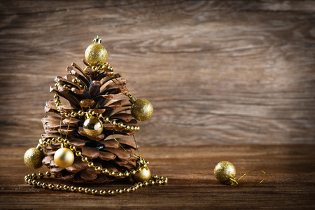 Big pine cone decorated with christmas golden balls and  beads garland on old wooden background with copy space.の写真素材