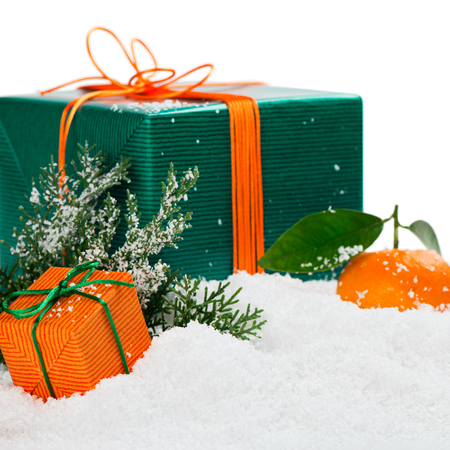 Christmas decoration, gift boxes and tangerines with green leaves on a snow background, isolated on white.の写真素材