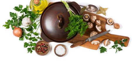Top view of cooking pot and uncooked ingredients for mushroom soup (fresh brown champignon mushrooms, olive oil, spices) on a cutting wooden board isolated on white background.の写真素材