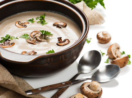 Close up of bowl with mushroom cream soup decorated with sliced champignons and green parsley isolated on white background.の写真素材