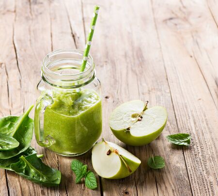 Green smoothie with spinach and apple in a jar mason on a old wooden background with copy space.の写真素材