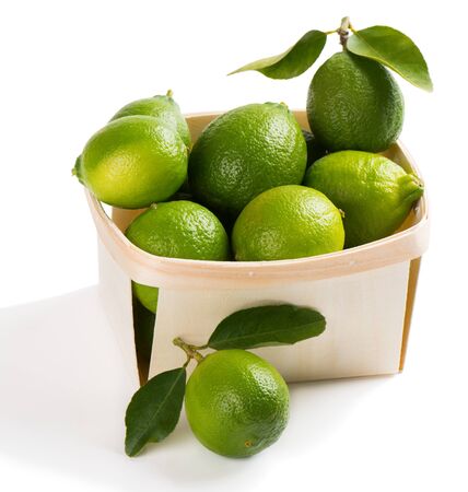 Crate of fresh lime fruits with leaves isolated on white background.の写真素材