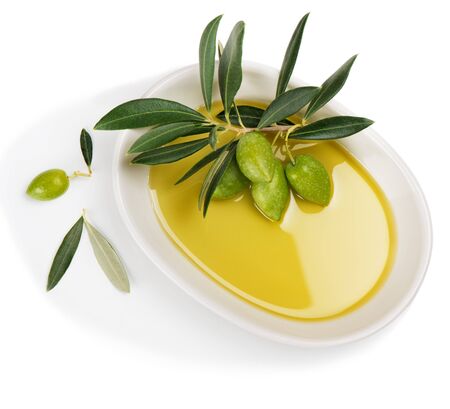 Top view of white ceramic bowl with olive oil and twig with green olive fruits isolated on white background.の写真素材