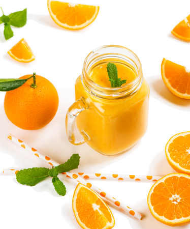 Fresh orange fruits with green leaves and orange smoothie in a jar mug isolated on white background.の写真素材