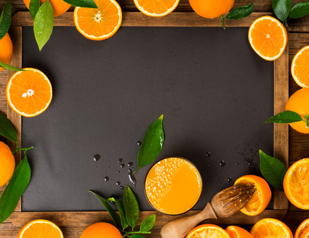 Orange juice with squeezed orange fruits on a blank blackboard with copy space.の写真素材