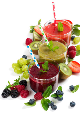 Fresh juices smoothie of summer fruits and berries - strawberry, raspberry, blueberry, blackberry, kiwi and grape in glasses with drinking straws isolated on white background. の写真素材