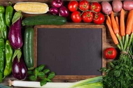 Blank menu board and vegetables ( potato, carrot,  onion, tomato,  zucchini, eggplant, corn,  pepper bell)  around on old wooden background. Top view.の写真素材