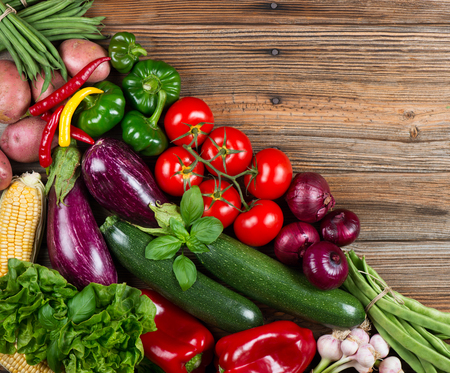 Top view of organic vegetables( potato, onion, tomato,  zucchini, eggplant, corn, garlic,  beans, pepper bell and chili ) on wooden rustic background with space.の写真素材