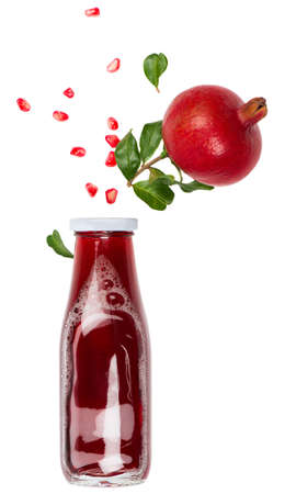 Glass bottle with pomegranate juice, whole pomegranate fruit and seeds isolated on a white background.の写真素材